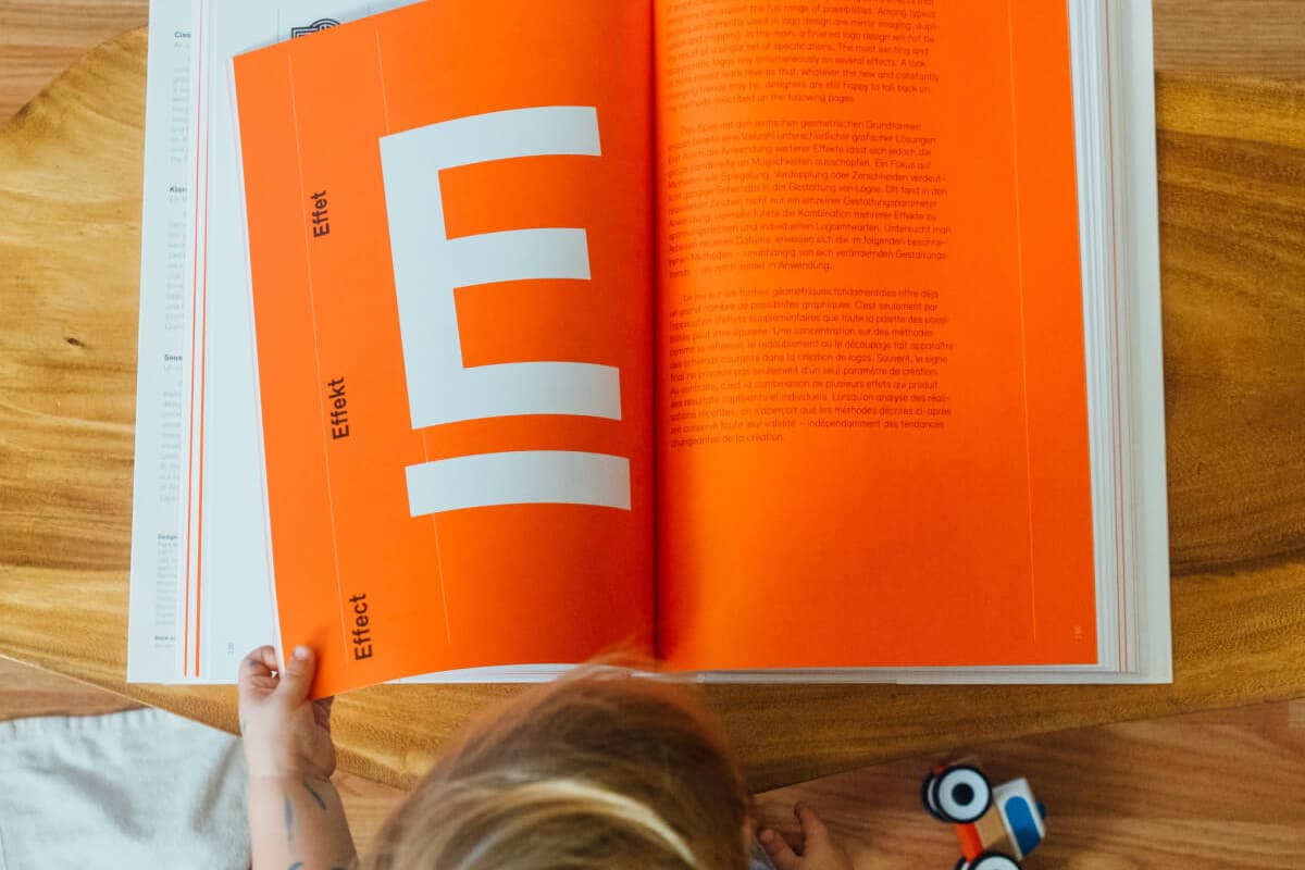 Child reading an orange book book-16@2x